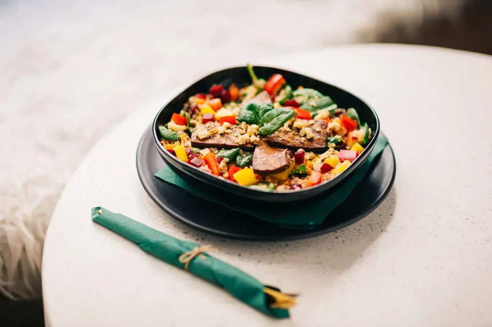 Colorful vegetable bowl with tofu on black plate, perfect for a healthy lifestyle.
